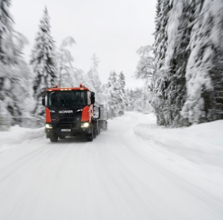 Orange truck driving on snowy winter road