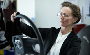 Woman holding and looking at a steering wheel