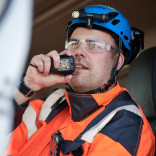 Man with  helmet and orange safety jacket talking in walkie talkie in truck