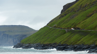 Green mountain with road next to the sea