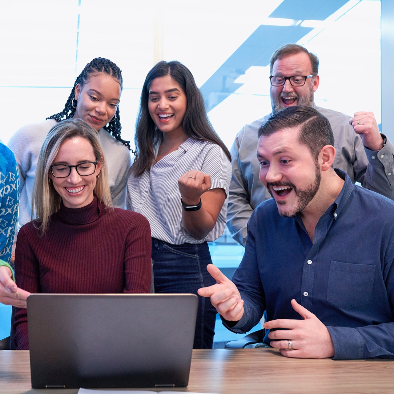 Five persons looking happy and excited in front of a laptop