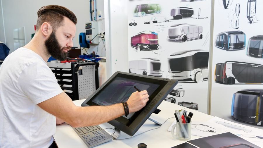 A man using a stylus to create vehicle designs on a touch screen
