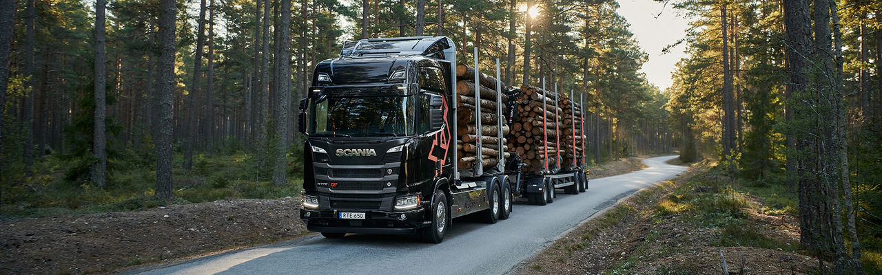  En Scania XT-lastbil för skogstransportsom kör timmer på en skogsväg