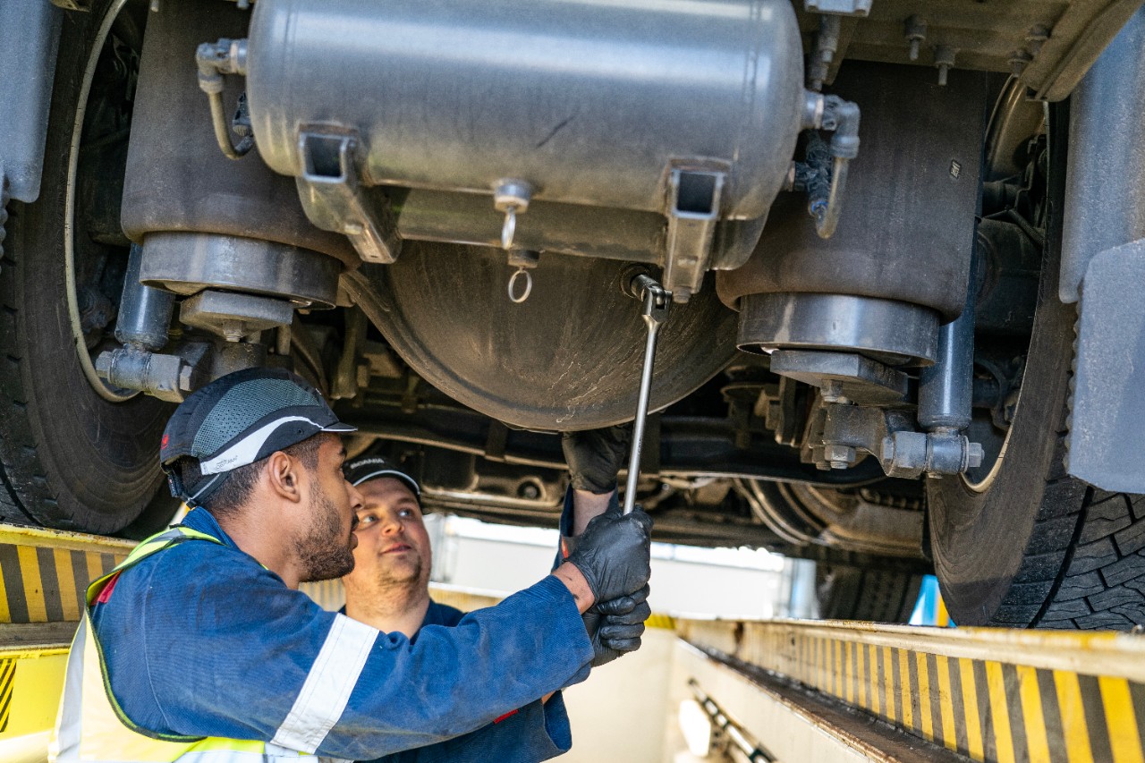Technician working under a truck in workshop
