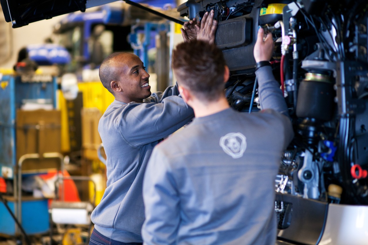 Technician working under a truck in workshop