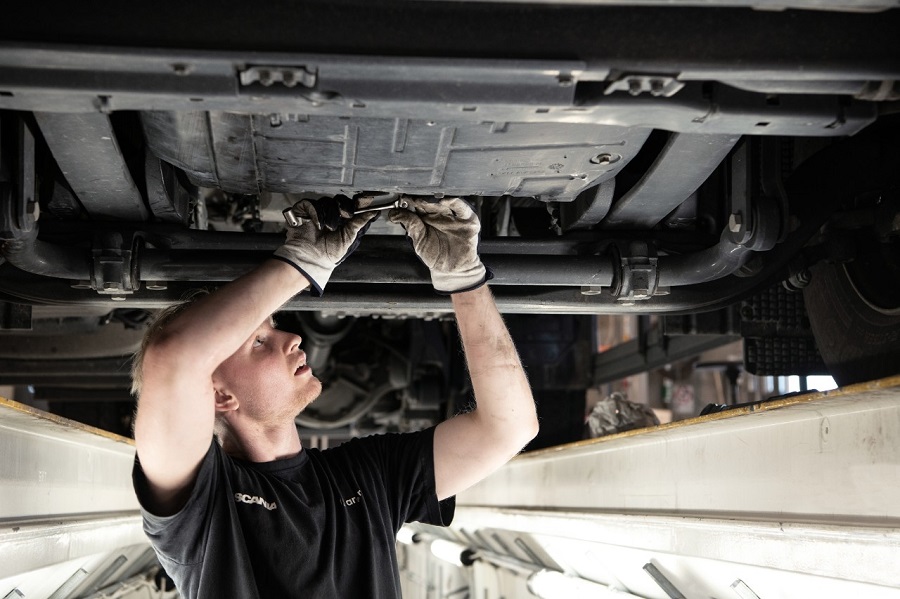 Technician working under a truck in workshop