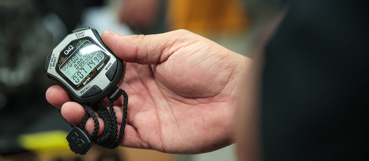a zoomed-in image of a hand holding a stopwatch.