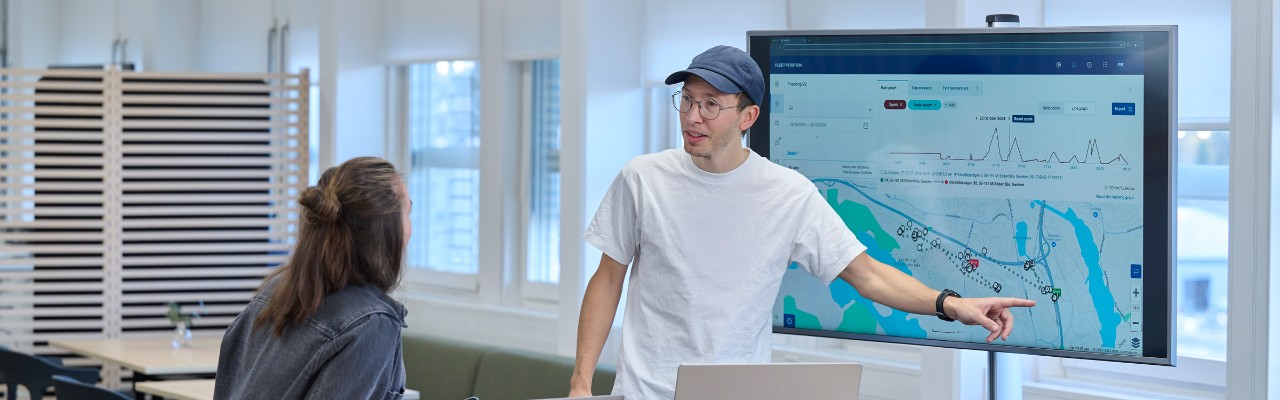 colleagues demonstrating mixed fleet connectivity app on screen